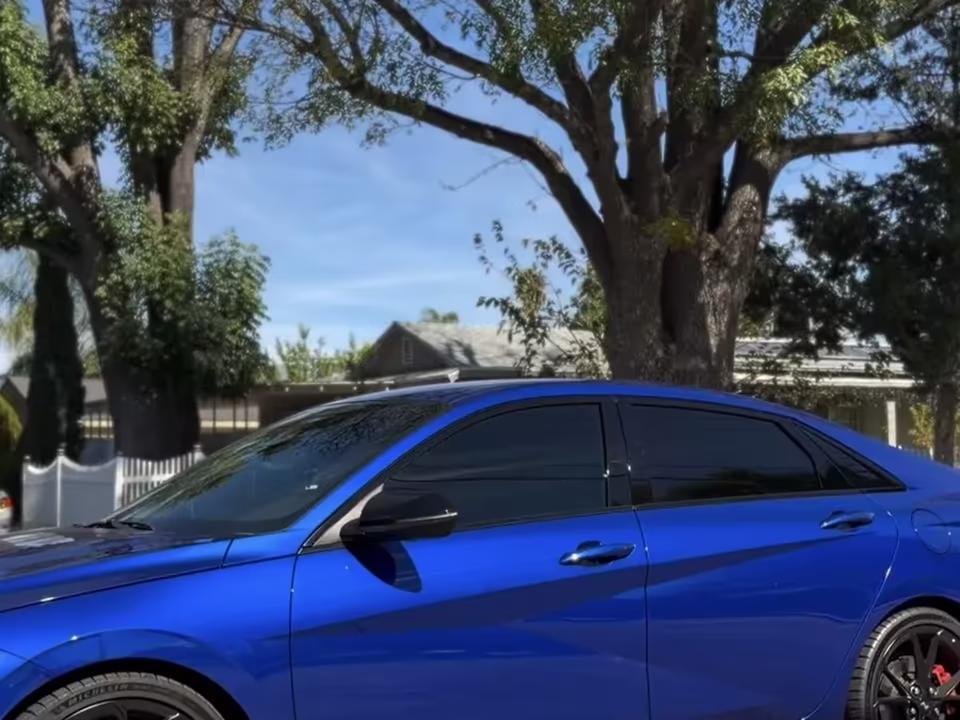 Blue sedan with dark ceramic tint on all side windows