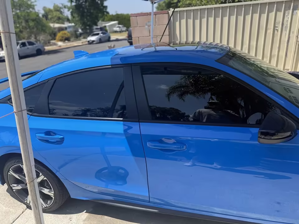 Close view of ceramic tint film edge on a blue hatchback door glass